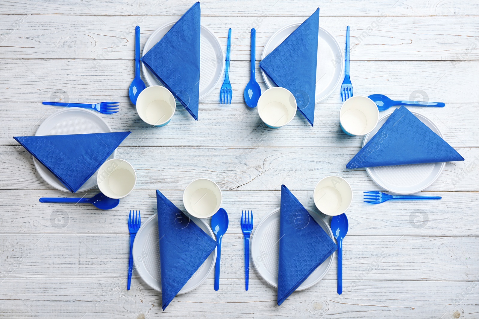 Photo of Table setting with plastic dishware on wooden background, flat lay