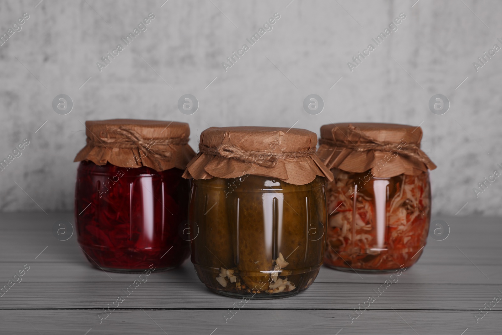 Photo of Glass jars with different preserved vegetables on wooden table
