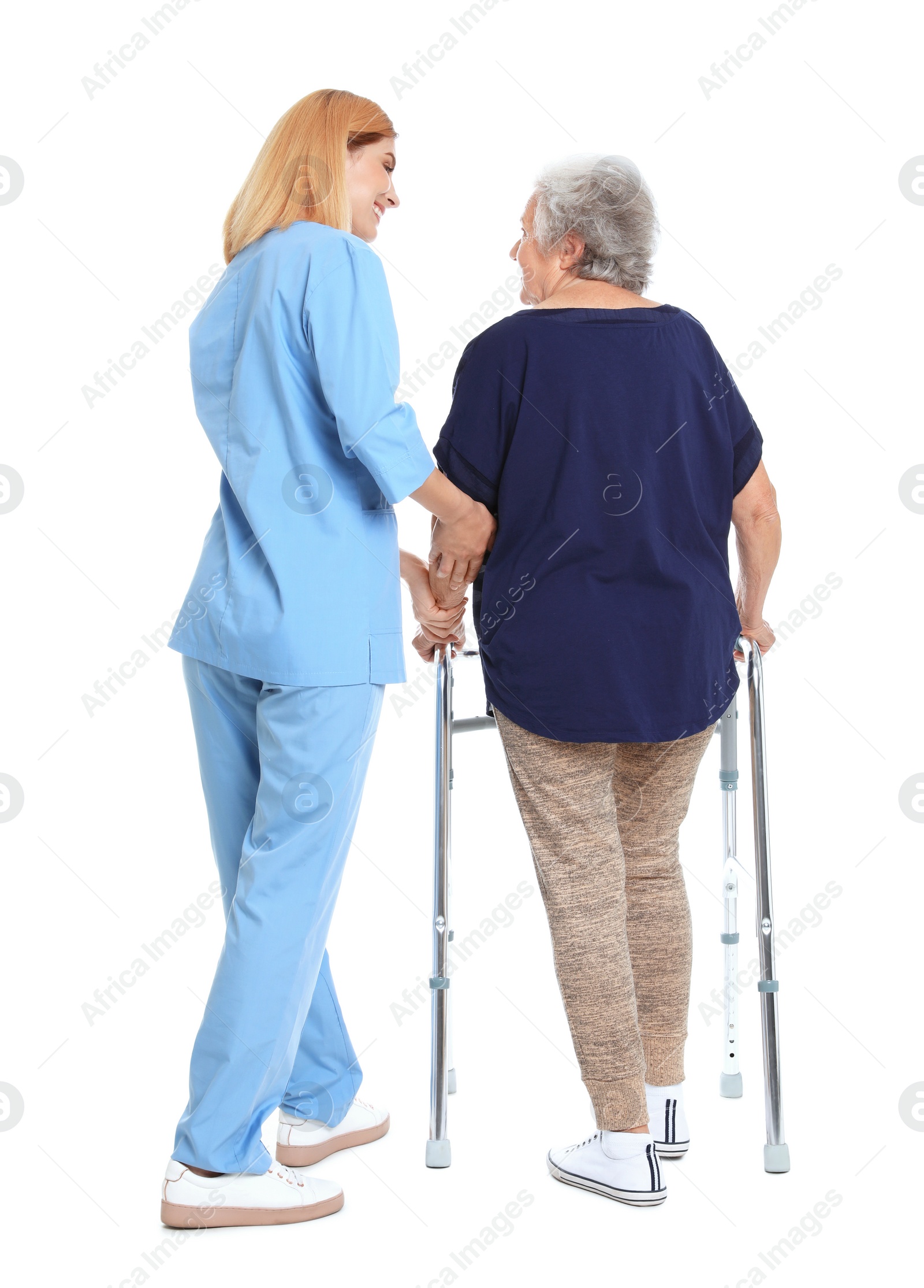 Photo of Caretaker helping elderly woman with walking frame on white background