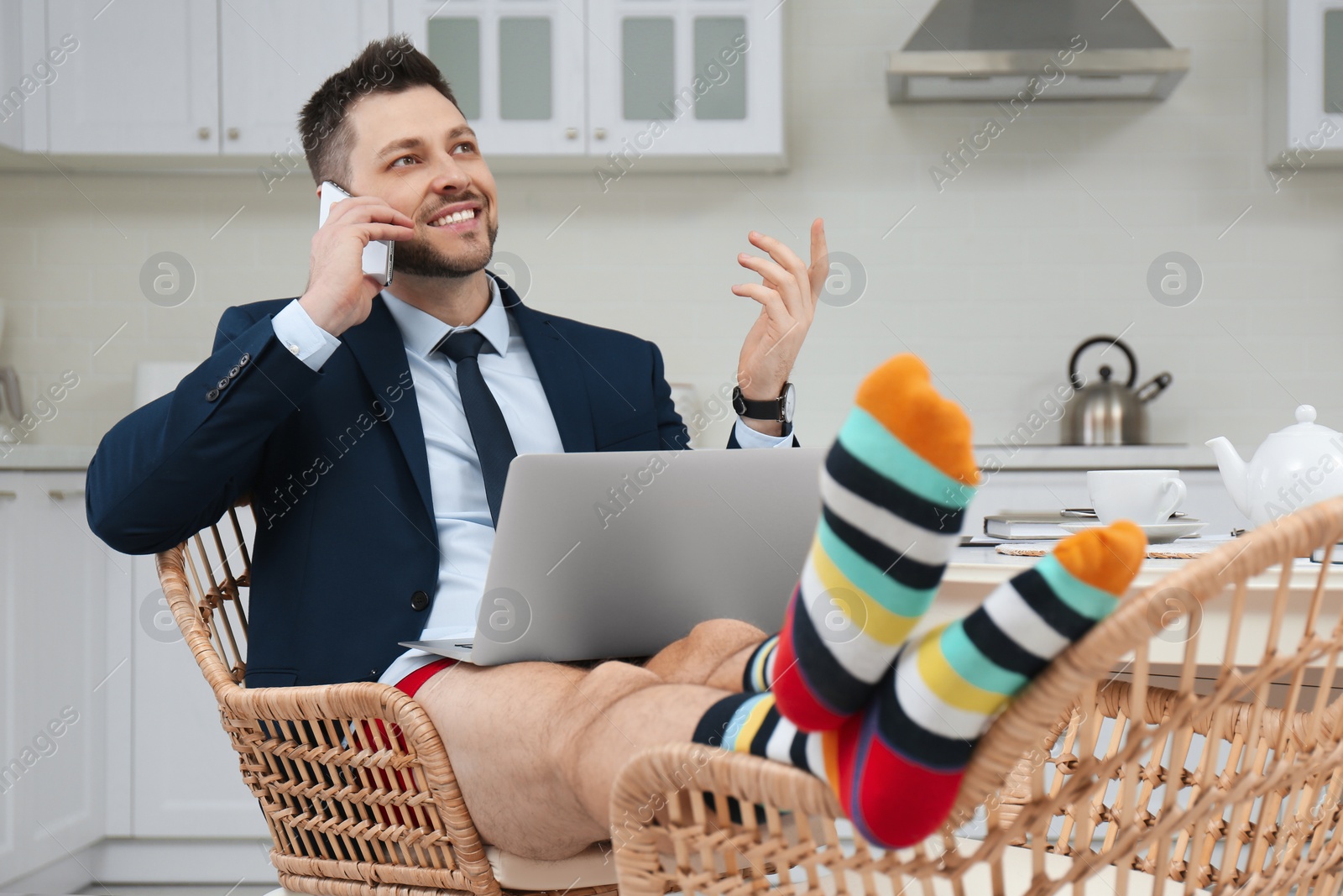 Photo of Businessman in shirt and underwear talking on phone during video call at home