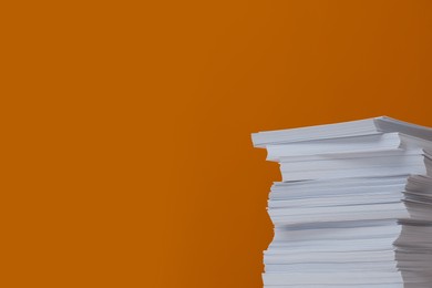 Photo of Stack of paper sheets on orange background. Space for text