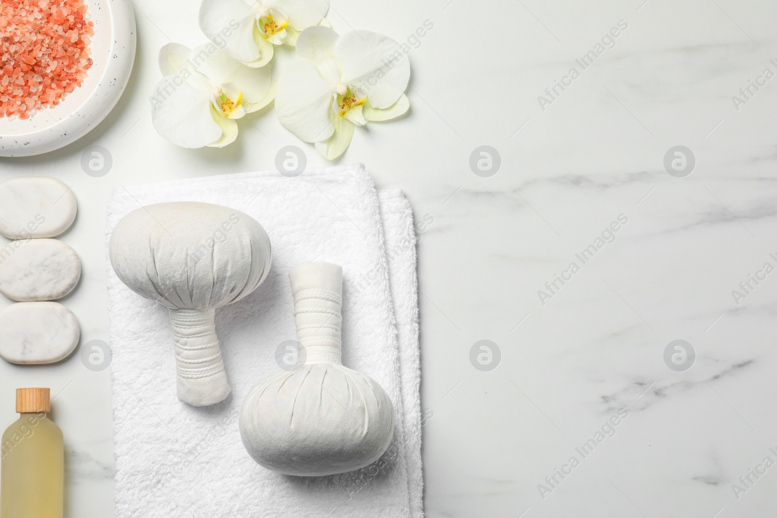 Photo of Spa bags, pink salt and essential oil on white marble table, flat lay. Space for text