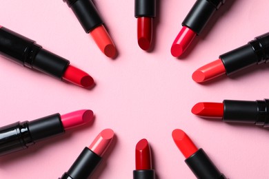 Photo of Frame of bright lipsticks on pink background, flat lay. Space for text