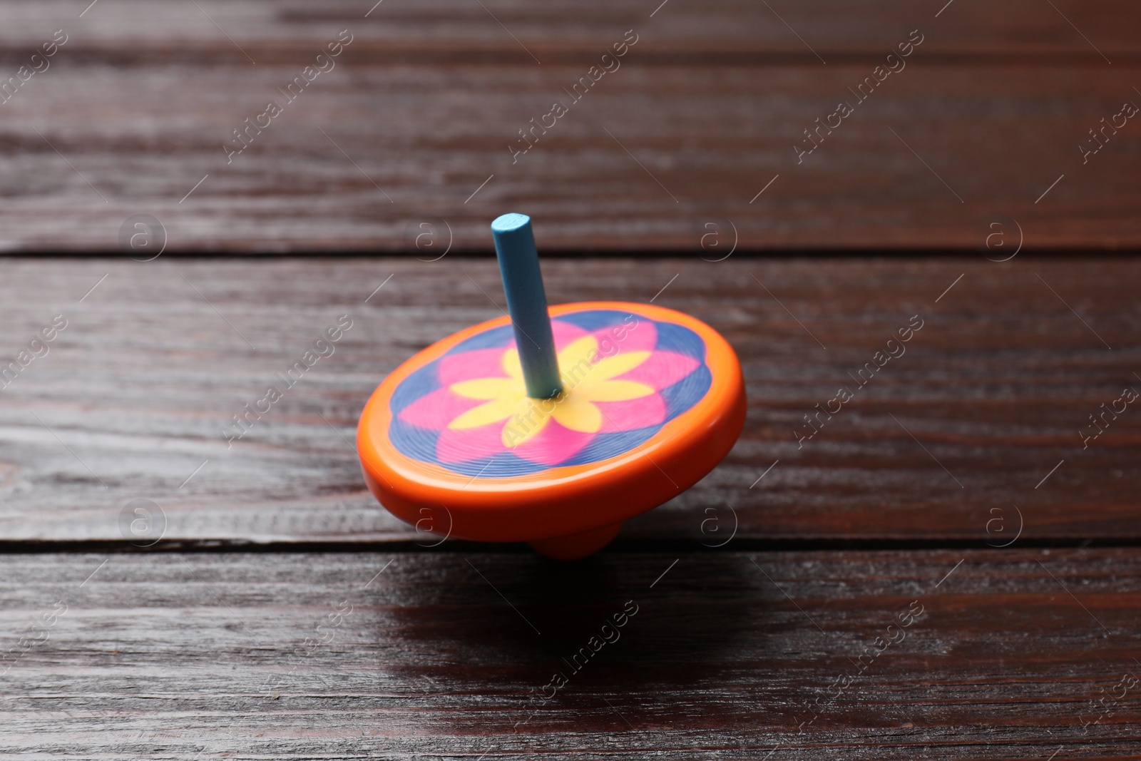 Photo of Bright spinning top on wooden table, closeup