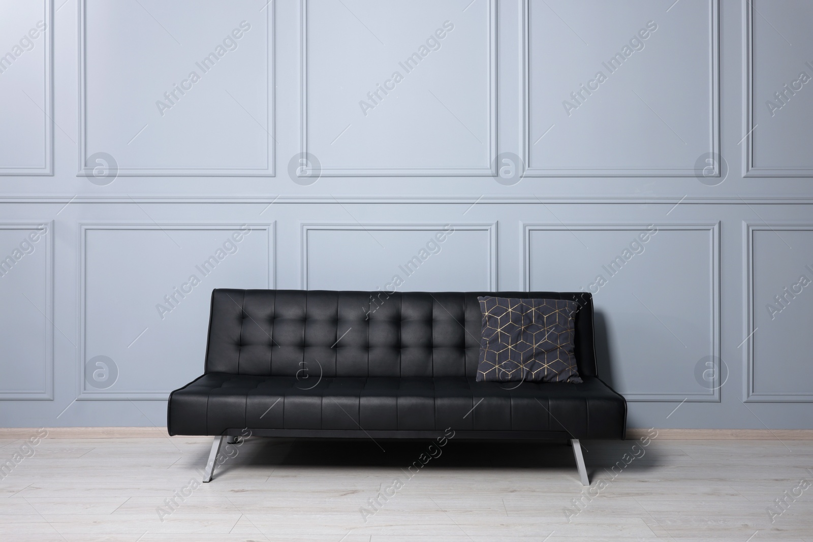 Photo of Stylish leather sofa near white wall in room. Interior design