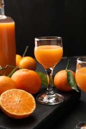 Photo of Tasty tangerine liqueur and fresh fruits on black table