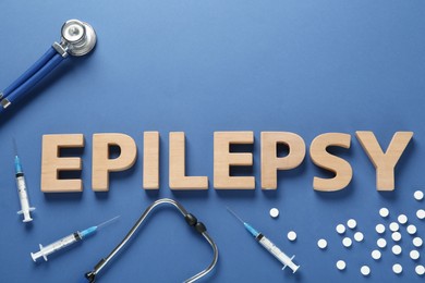 Photo of Word Epilepsy made of wooden letters, stethoscope, pills and syringes on blue background, flat lay