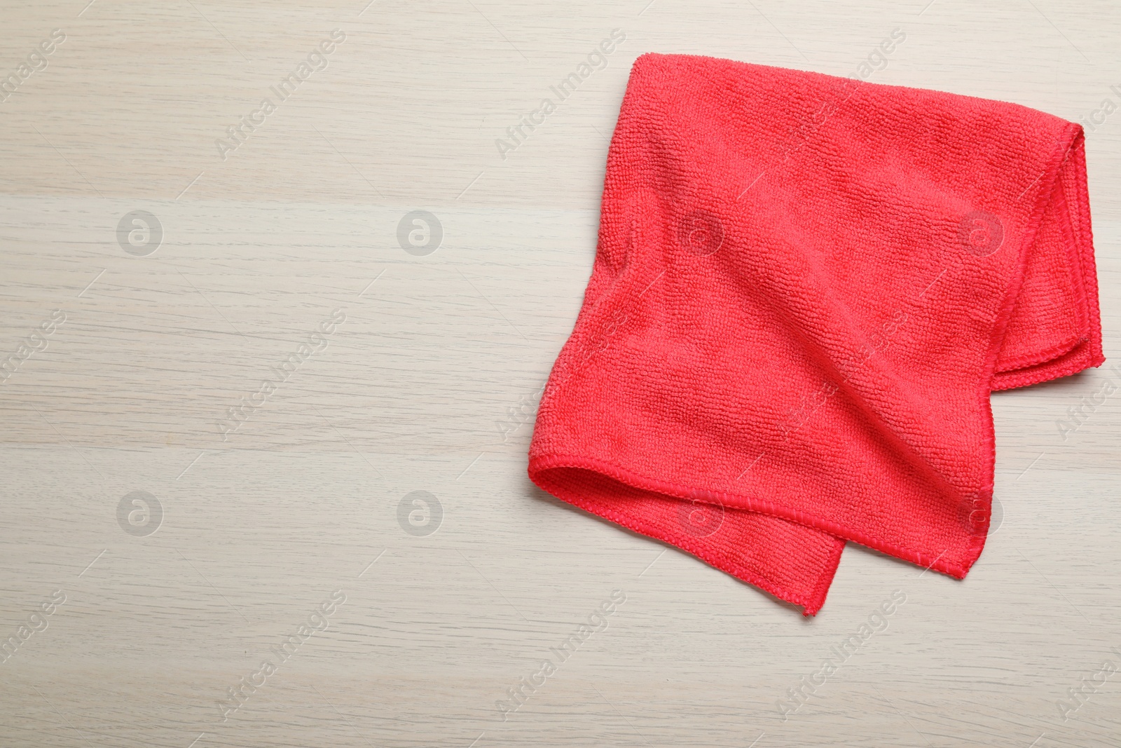 Photo of Red microfiber cloth on light wooden background, top view. Space for text