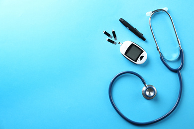 Photo of Flat lay composition with glucose meter and stethoscope on light blue background. Space for text