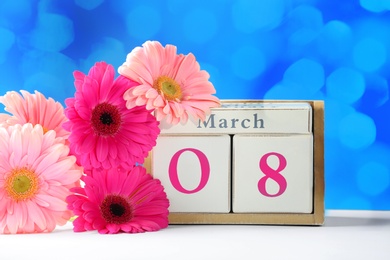 Photo of Calendar and flowers on table against color background. International Women's Day