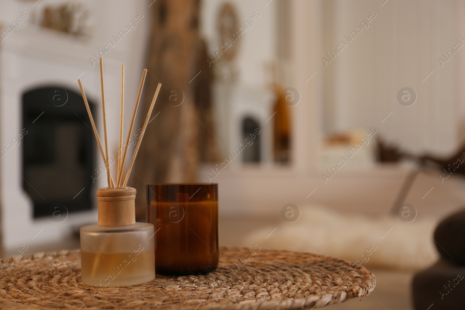 Photo of Aromatic reed air freshener and candle on wicker tray in room. Space for text