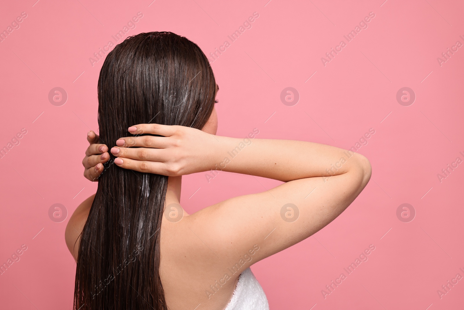 Photo of Woman applying hair mask on pink background. Space for text