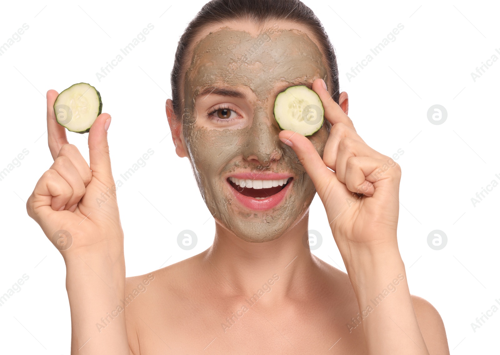 Photo of Beautiful woman with clay mask holding pieces of cucumber on white background