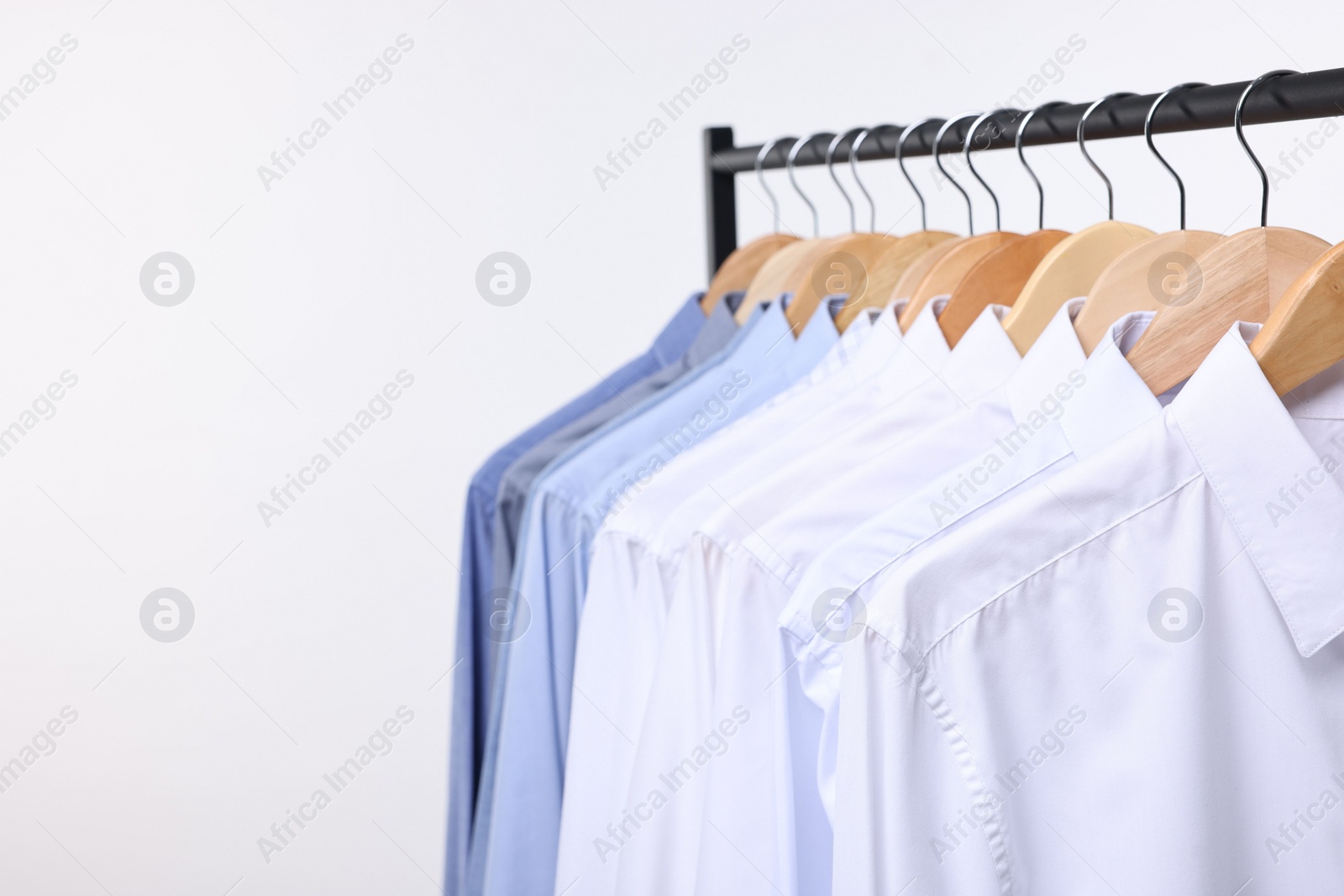 Photo of Dry-cleaning service. Many different clothes hanging on rack against white background, space for text