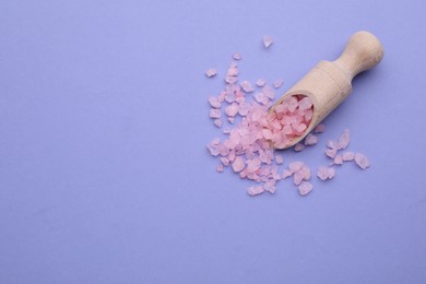 Photo of Scoop with pink sea salt on violet background, top view. Space for text