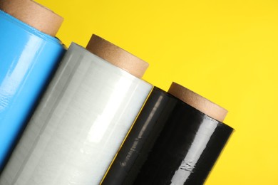 Photo of Rolls of different stretch wrap on yellow background, closeup