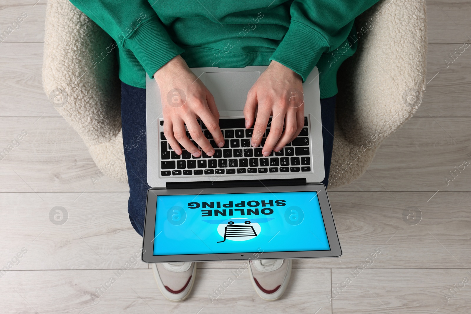 Image of Man using laptop for online shopping in armchair indoors, top view