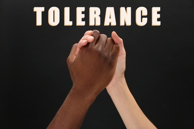Image of Tolerance, support and cooperation concept. Woman and man of different races clasping hands on black background, closeup