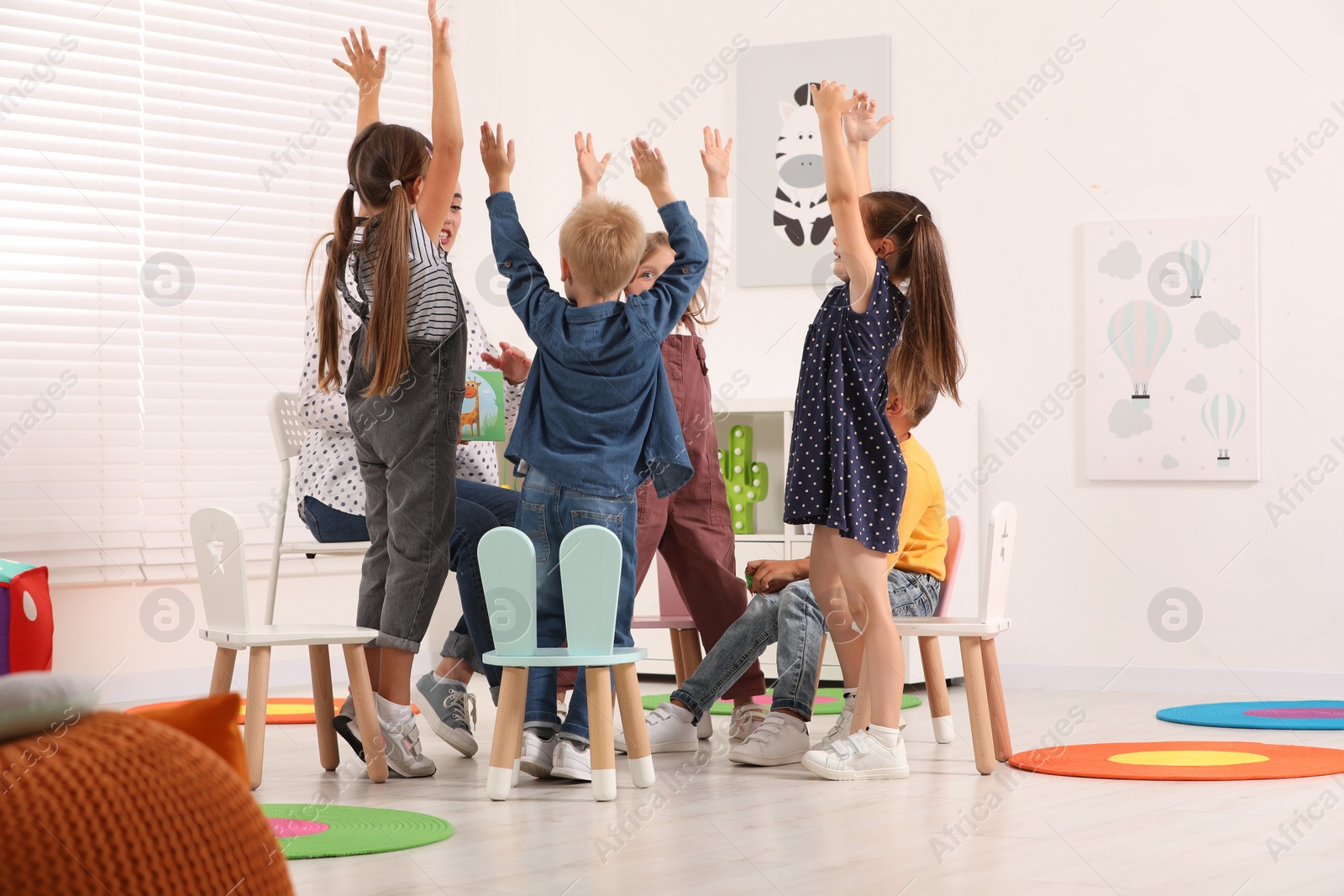 Photo of Nursery teacher and group of cute little children studying with fun in kindergarten. Playtime activities