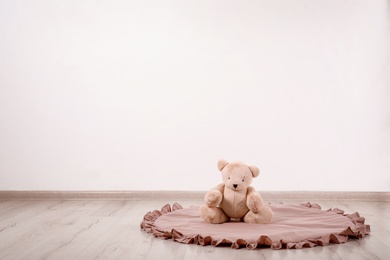 Photo of Teddy bear and rug on floor in child room. Space for text