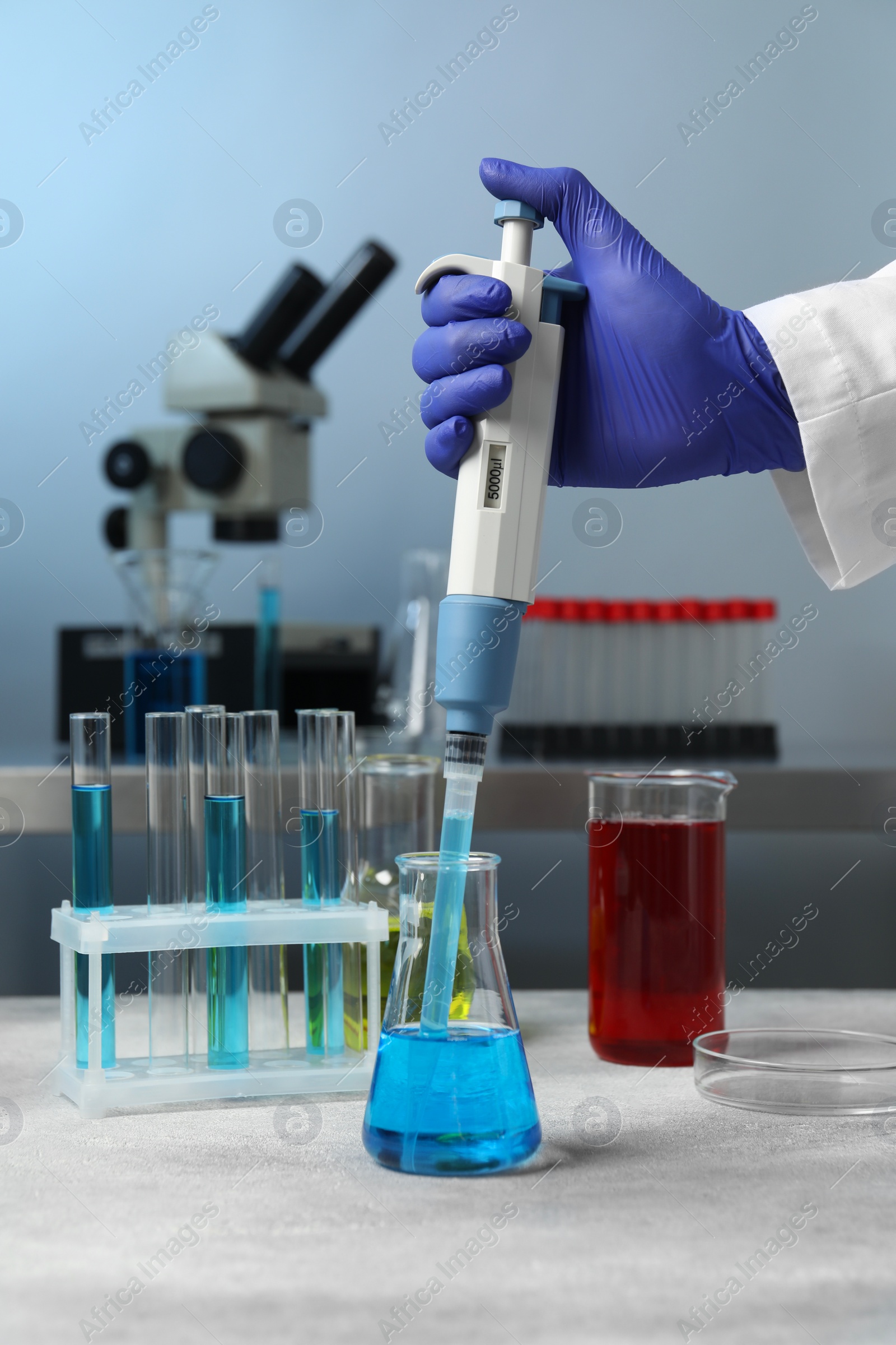 Photo of Laboratory analysis. Scientist dripping sample with micropipette into flask indoors, closeup