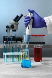 Photo of Laboratory analysis. Scientist dripping sample with micropipette into flask indoors, closeup