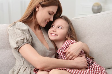 Photo of Mother and her cute daughter on sofa at home