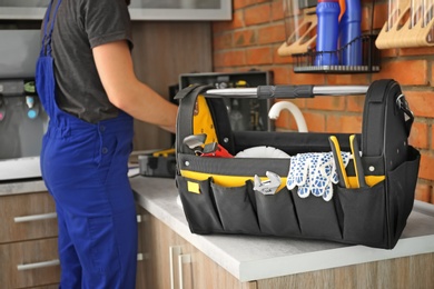 Photo of Set of professional tools and plumber in uniform indoors