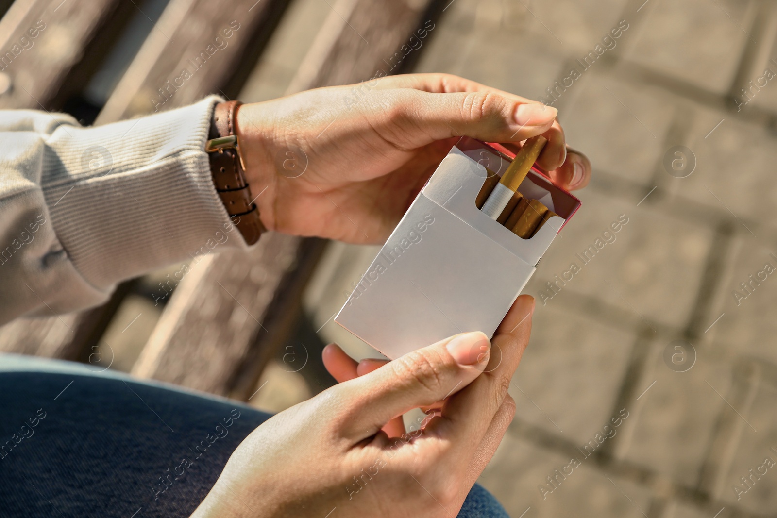 Photo of Woman taking cigarette out of pack outdoors, closeup