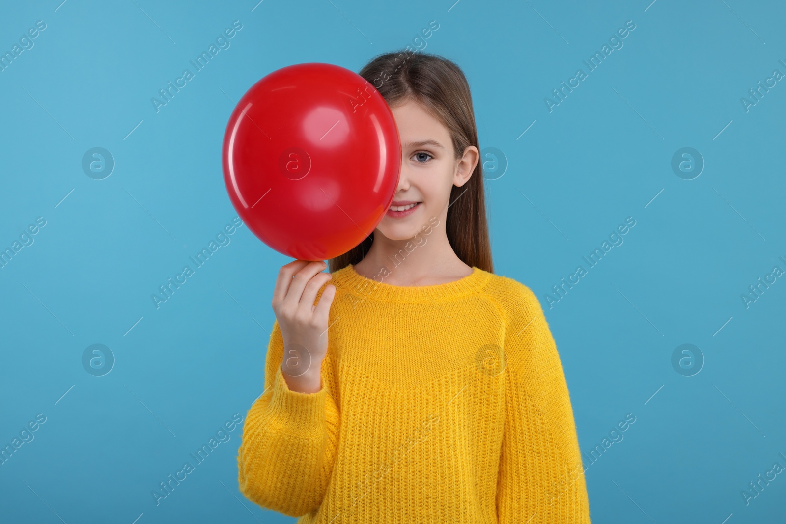 Photo of Happy girl with red balloon on light blue background