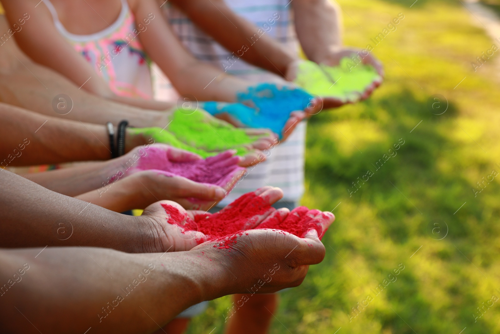 Photo of Friends with colorful powder dyes outdoors, closeup. Holi festival celebration