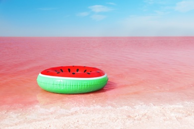 Bright inflatable ring floating in pink lake on summer day