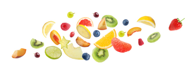 Image of Set of different cut fresh fruits and berries falling on white background. Banner design