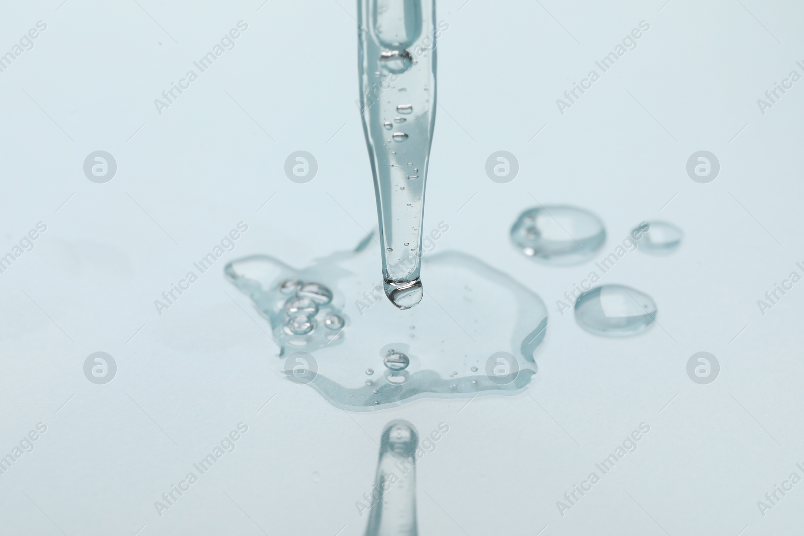 Photo of Glass pipette and transparent liquid on light background, closeup