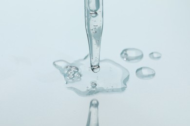 Photo of Glass pipette and transparent liquid on light background, closeup