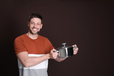 Photo of Happy man with pot on dark background. Space for text