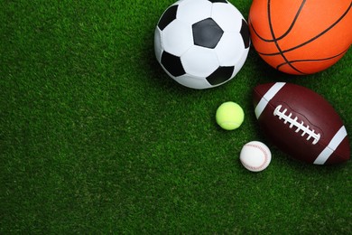 Photo of Set of different sport balls on green grass, flat lay. Space for text