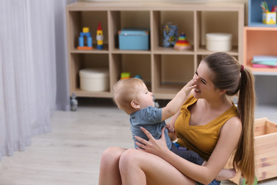 Photo of Teen nanny playing with cute little baby at home