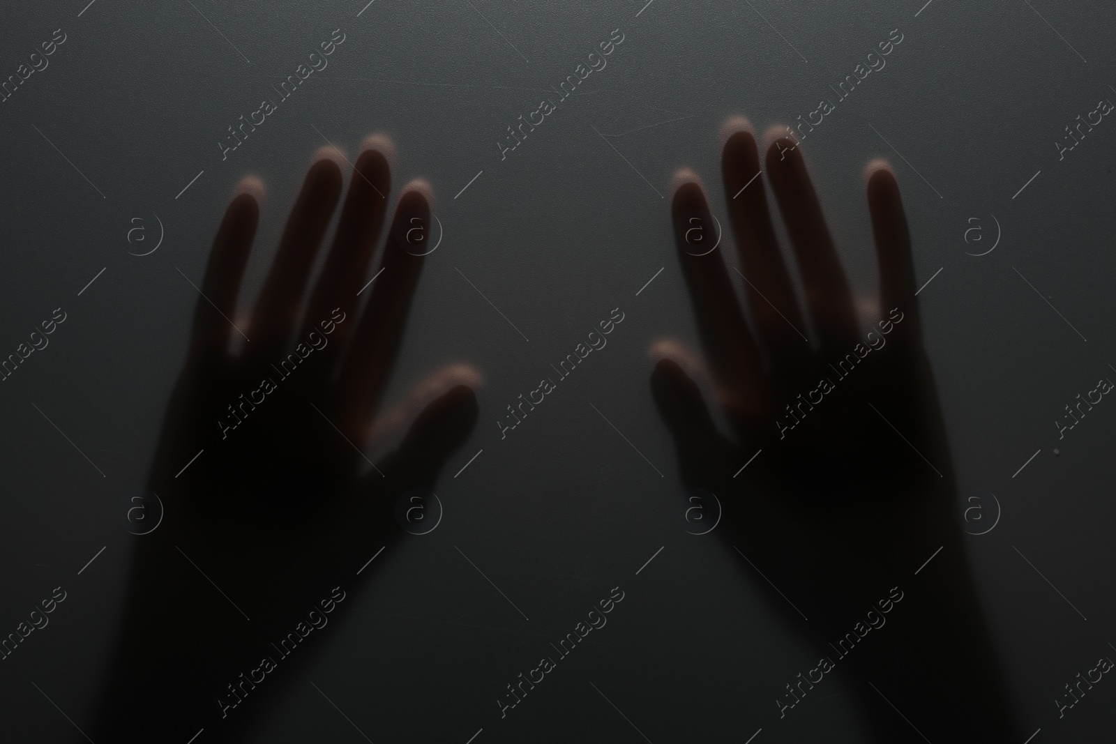 Photo of Silhouette of creepy ghost behind glass against grey background, closeup