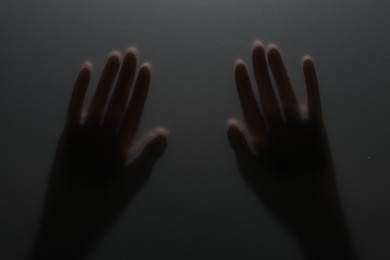 Photo of Silhouette of creepy ghost behind glass against grey background, closeup