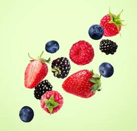 Image of Many different fresh berries falling on pale green background