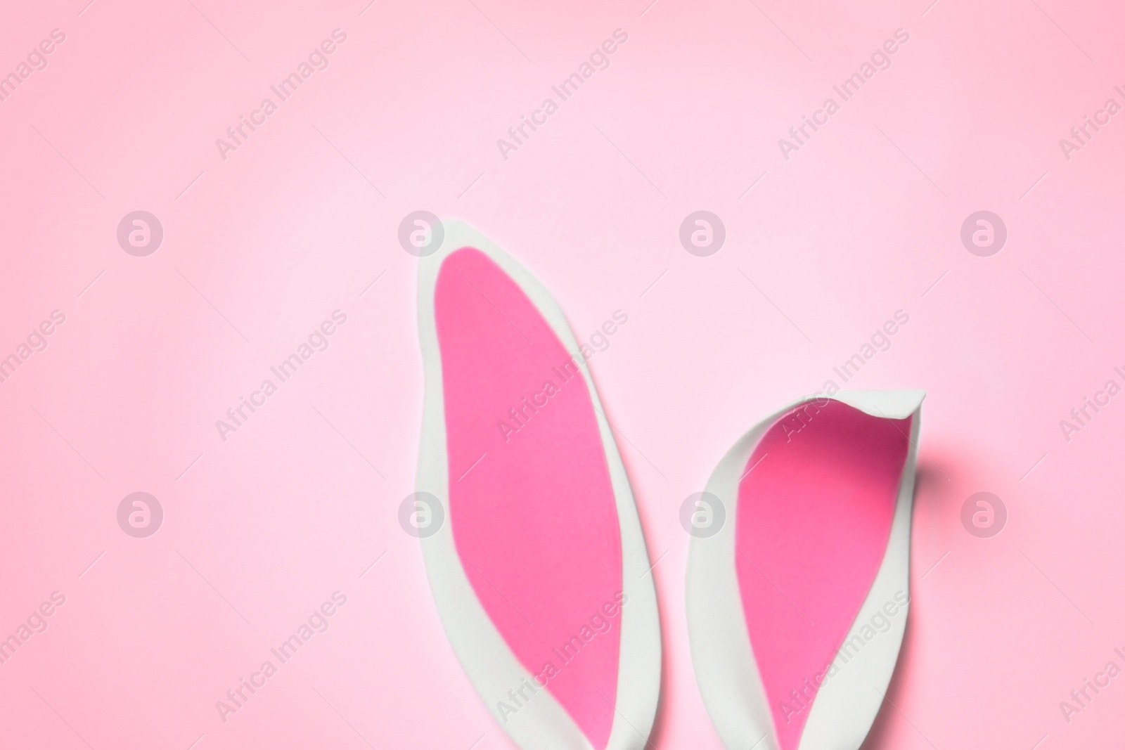 Photo of Funny Easter bunny ears on color background, top view with space for text