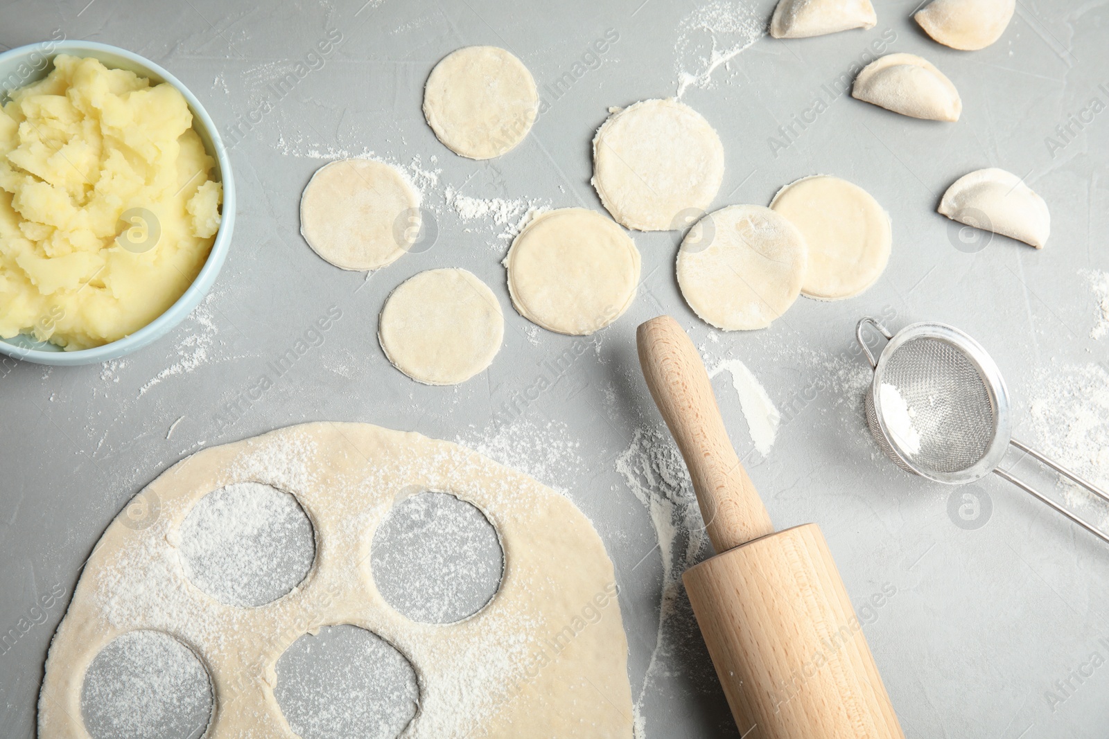 Photo of Flat lay composition with raw dumplings and dough on grey background. Process of cooking