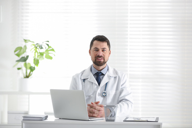 Photo of Portrait of male doctor in white coat at workplace