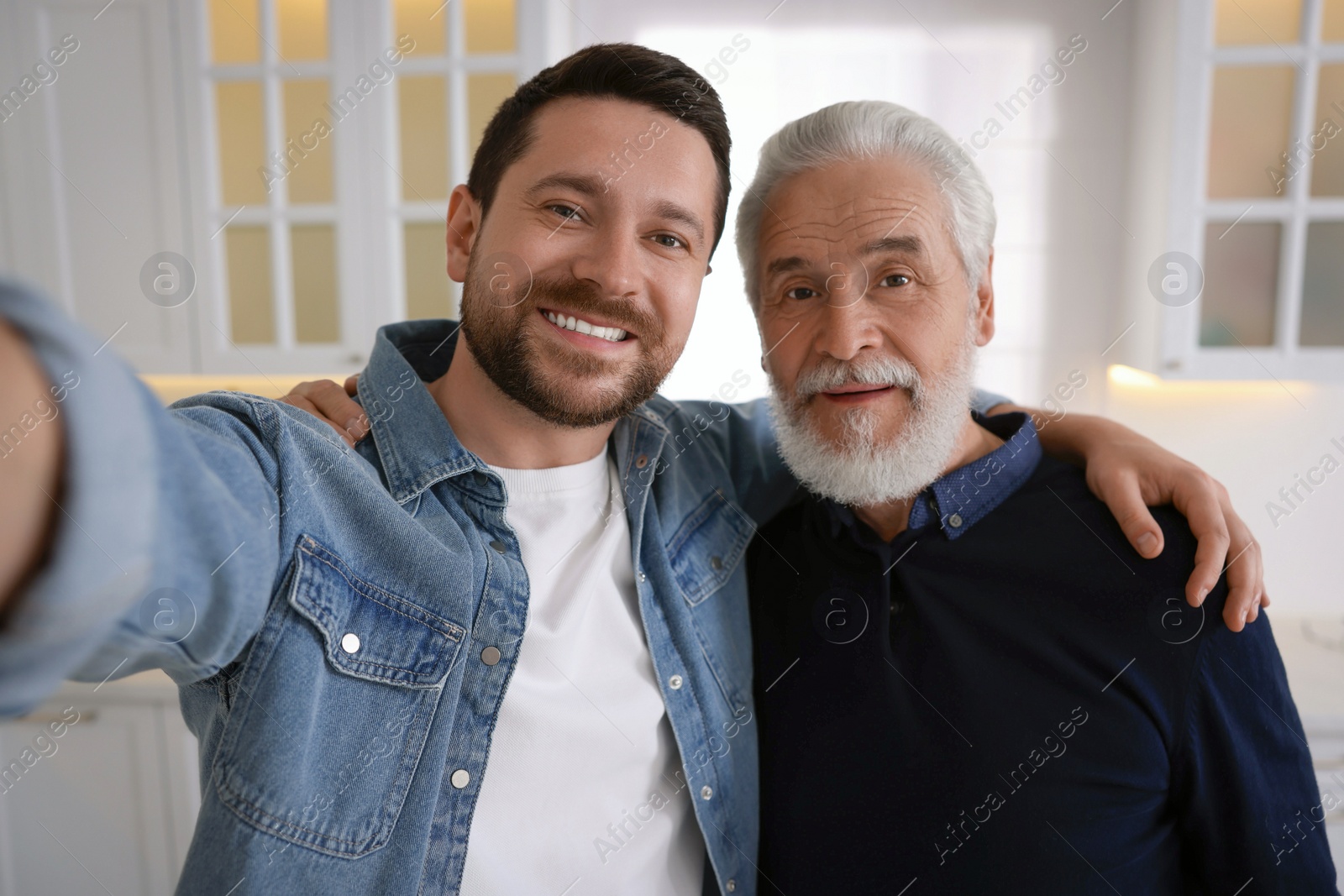 Photo of Happy son and his dad taking selfie at home