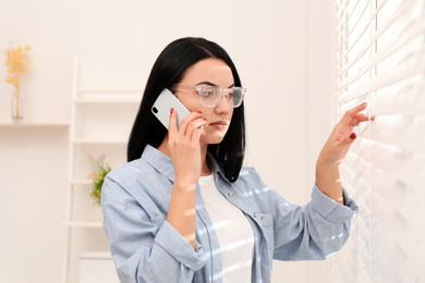 Beautiful young woman talking on phone indoors