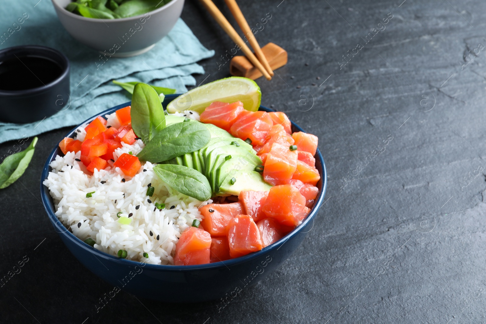 Photo of Delicious poke bowl with salmon, spinach and avocado served on black table. Space for text