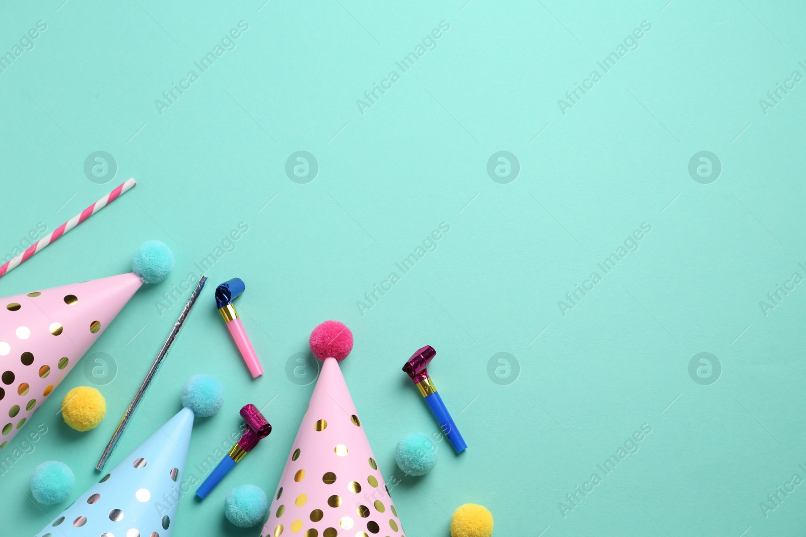 Photo of Party hats and other bright decor on turquoise background, flat lay. Space for text