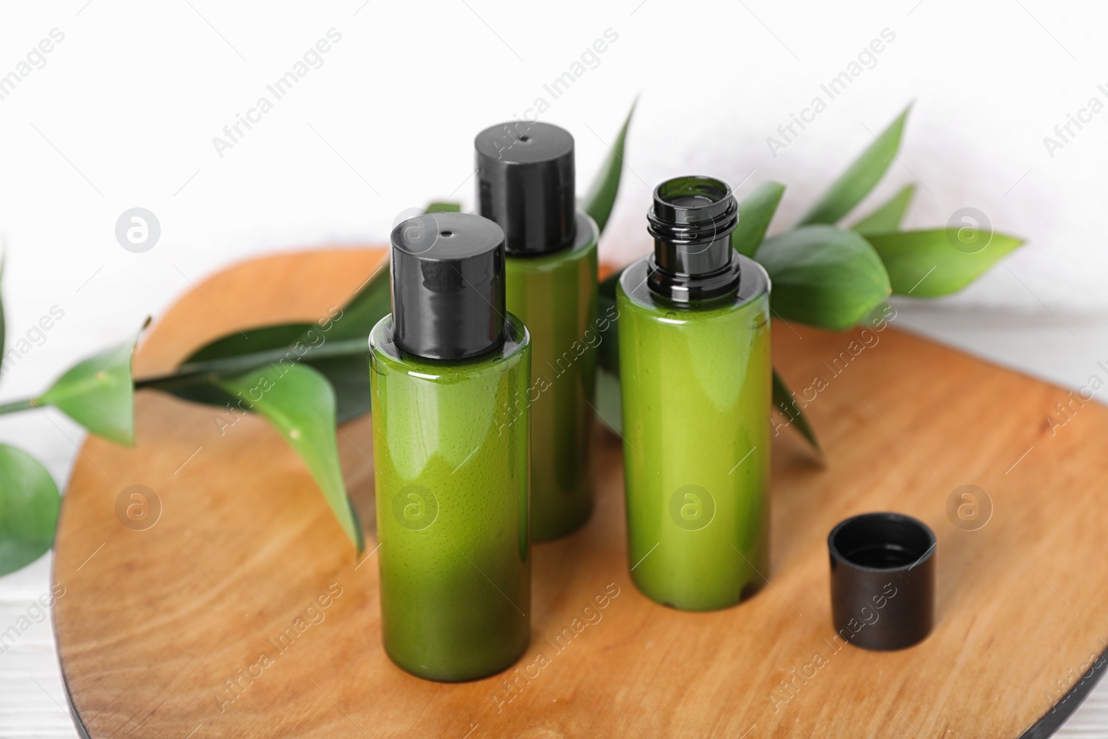 Photo of Mini bottles with cosmetic products on wooden plate