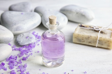 Photo of Bottle with natural herbal oil, soap and lavender flowers on wooden background